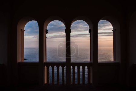 Foto de Puesta de sol sobre el mar a través de una ventana arqueada - Imagen libre de derechos