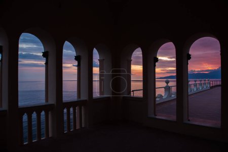 Foto de Puesta de sol sobre el mar a través de ventanas arqueadas - Imagen libre de derechos