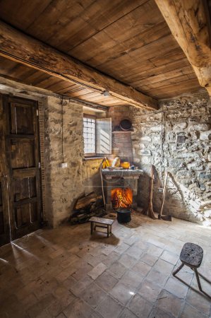 Téléchargez les photos : Cheminée allumée et ustensiles dans la maison de l'agriculteur avec cheminée - en image libre de droit