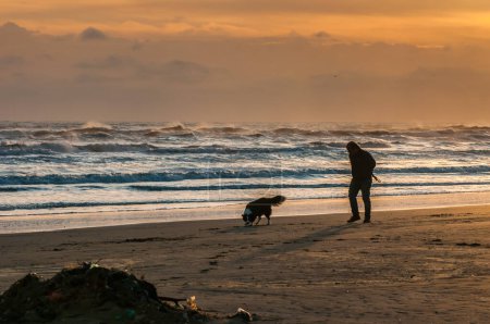 Foto de Man walking around on the beach at sunrise - Imagen libre de derechos