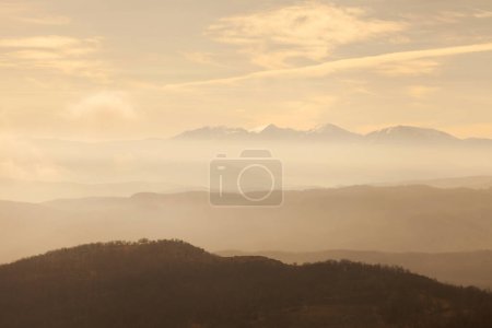 Photo for Cloudy sky and overlapping layers of the contours of the mountains, aerial perspective and outline of the mountains with haze and clouds - Royalty Free Image