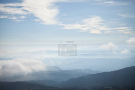 Photo for Cloudy sky and overlapping layers of the contours of the mountains, aerial perspective and outline of the mountains with haze and clouds - Royalty Free Image