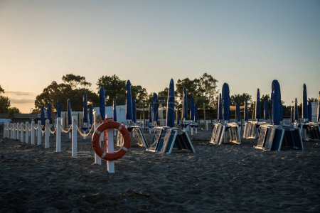 Foto de Tumbonas y sombrillas en la costa en la luz del atardecer - Imagen libre de derechos