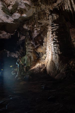 Foto de Cavers inspect the cave with a light bulb looking for stalactites and stalagmites - Imagen libre de derechos