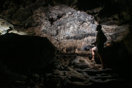 Téléchargez les photos : Cavers inspect the cave with a light bulb looking for stalactites and stalagmites - en image libre de droit
