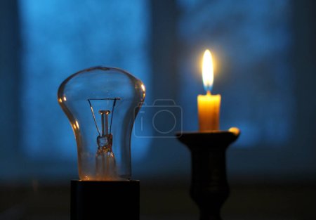 Téléchargez les photos : Dans le noir, quand il n'y a pas d'alimentation électrique, une bougie est allumée - en image libre de droit