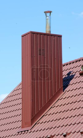 Téléchargez les photos : Une cheminée sur le toit d'une maison recouverte de tuiles métalliques ou d'un profil métallique - en image libre de droit