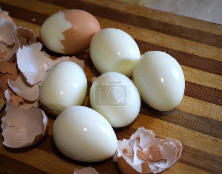 On the kitchen board, hard-boiled chicken eggs are peeled