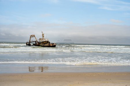 Foto de The thrown old ship has sat down on a bank - Namib desert with Atlantic ocean meets near Skeleton coast - Namibia, South Africa - Imagen libre de derechos