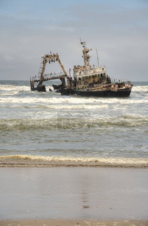 Foto de The thrown old ship has sat down on a bank - Namib desert with Atlantic ocean meets near Skeleton coast - Namibia, South Africa - Imagen libre de derechos