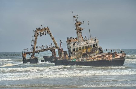 Foto de El viejo barco arrojado se ha sentado en la orilla - el desierto de Namib con el océano Atlántico se encuentra cerca de la costa Esqueleto - Namibia, Sudáfrica - Imagen libre de derechos