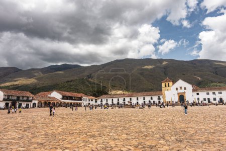 Foto de Villa de Leyva, Colombia - 20 de abril de 2019: Turistas alojados en la plaza de la ciudad histórica durante el día nublado. - Imagen libre de derechos