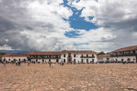 Foto de Villa de Leyva, Colombia - 20 de abril de 2019: Turistas alojados en la plaza de la ciudad histórica durante el día nublado. - Imagen libre de derechos