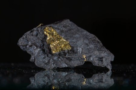 A piece of gold nugget on a black background with reflection.