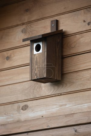 Vogelhäuschen aus Holz an einer Holzwand, Nahaufnahme.