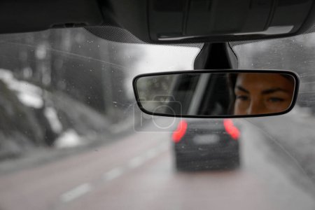 Photo for Reflection of a woman in a rear view mirror inside a car - Royalty Free Image
