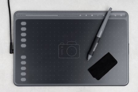 Photo for Top view of drawing tablet and stylus and piece of fabric on grey background - Royalty Free Image