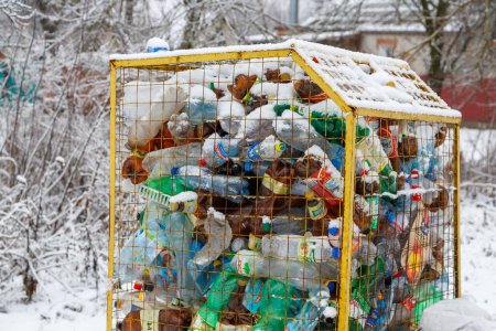Ukraine, city of Romny, December 26, 2022: Plastic bottles in a trash can, waste management concept. A container for plastic bottles on a winter snowy street. Waste recycling concept puzzle 632425818
