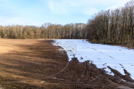 Melting snow on a plowed field in early spring. Fertile black soil