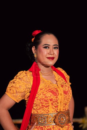 Foto de Mujeres indonesias exóticas con labios rojos y maquillaje mientras usan un vestido naranja y una bufanda roja durante el festival de danza tradicional - Imagen libre de derechos