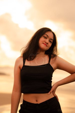 Photo for An Asian teenage girl in a black shirt looks very happy as can be seen from her expression while on vacation by the beach in the afternoon - Royalty Free Image