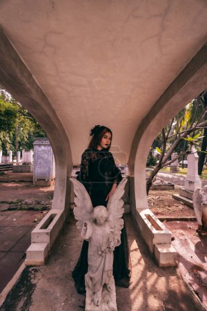 Photo for An Asian woman dressed all in black and a scary face was standing over the cemetery in the late afternoon - Royalty Free Image