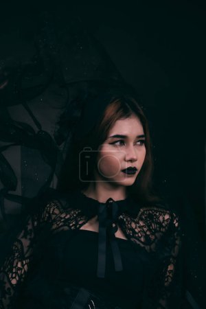 Photo for An Asian teenager has a scary appearance with all-black makeup and a black dress like a witch before Halloween at night - Royalty Free Image