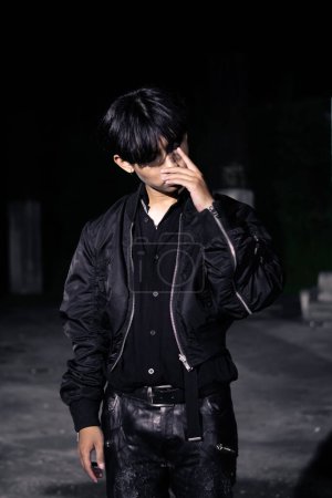 Photo for An asian man in a black parachute jacket posing very manly in a building at night - Royalty Free Image