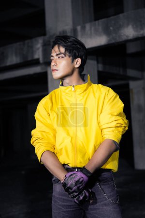 Photo for An asian man with a yellow jacket and black hair posing very gallantly in an abandoned building - Royalty Free Image