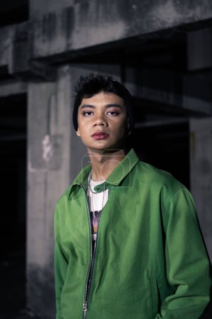 Téléchargez les photos : Un homme asiatique se tient debout dans un bâtiment abandonné dans une tenue excentrique la nuit - en image libre de droit