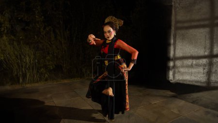 Photo for A Sundanese dancer wears a beautiful sparkling red costume and dances with a passionate expression at the night - Royalty Free Image