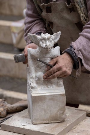 Foto de Primer plano del escultor trabajando en una pieza usando martillo y cincel, esculpiendo una piedra de mármol blanco en una hermosa escultura - Imagen libre de derechos
