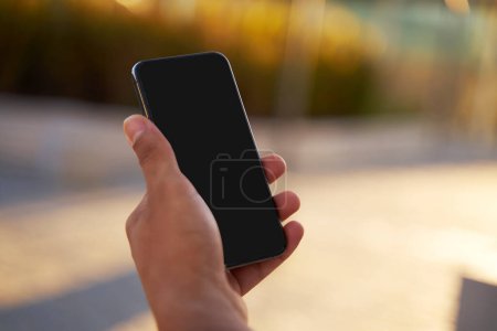 Foto de Primer plano de la mano sosteniendo el teléfono móvil con pantalla en blanco, enfoque selectivo. Concepto tecnológico - Imagen libre de derechos