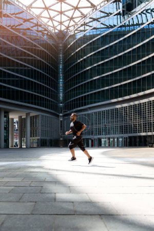 Téléchargez les photos : Homme actif et sportif qui court en ville. Vue verticale de l'entraînement des hommes iraniens dans la ville. Mouvement dynamique. Sport et mode de vie sain - en image libre de droit