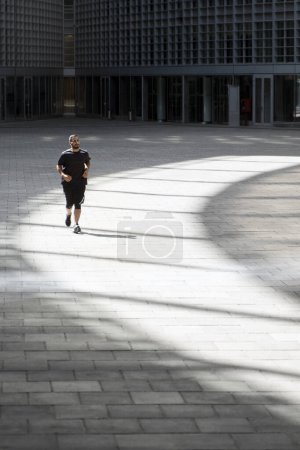 Photo for Sportive active man running at urban place. Vertical view of iranian guy training in the city. Dynamic movement. Sports and healthy lifestyle - Royalty Free Image