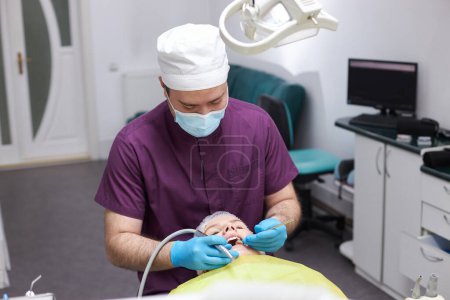 Photo for Male dentist wearing protective face mask, using dental instruments for oral care check up. Doctor examining for cavities and gum disease. Medical occupation service and health care in dental clinic - Royalty Free Image