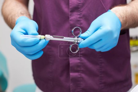Foto de Primer plano de una jeringa con aneasthetic dental en manos del dentista doctor. - Imagen libre de derechos