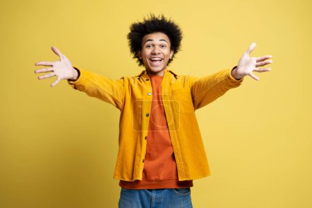 Téléchargez les photos : Amical homme afro-américain tenant les bras ouverts prêts pour des câlins isolés sur fond jaune - en image libre de droit