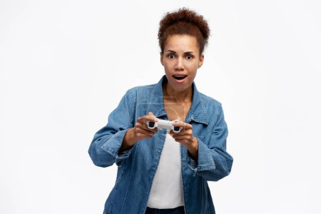 Foto de Emocionado jugador afroamericano mujer jugando videojuego usando joystick sobre fondo blanco aislado. Mujer feliz mirando a la cámara - Imagen libre de derechos