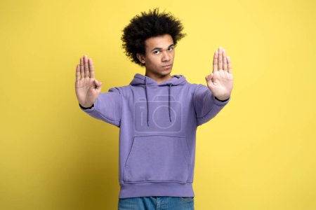 Photo for Serious concerned man making stop gesture showing palm of hand, conflict prohibition warning about danger, stop bullying. Indoor studio shot isolated on yellow background - Royalty Free Image