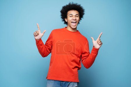 Photo for Happy emotional African American man screaming, dancing and rejoicing isolated on blue background. Music and having fun concept - Royalty Free Image