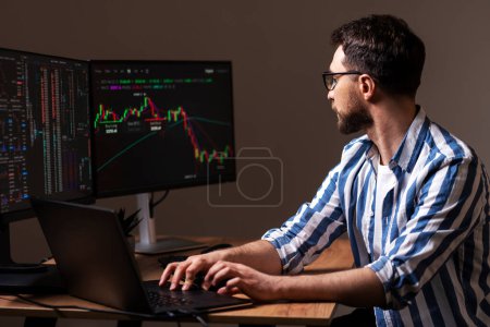 Photo for Serious trader typing on keyboard looking at computer monitor, working online with crypto chart sitting in modern office. Successful business, online trading concept - Royalty Free Image
