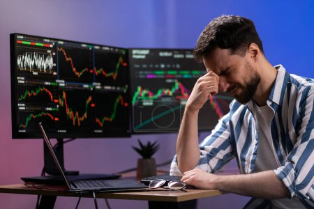 Photo for Tired overworked bearded man, crypto trader having headache, lost money, working late night sitting in office. Failure business, bankruptcy concept - Royalty Free Image