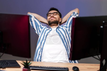Photo for Happy handsome freelancer leaning back, relaxing, having break sitting at workplace. Successful business - Royalty Free Image