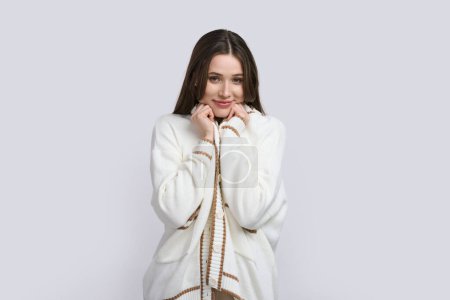 Photo for Confident portrait of beautiful Caucasian young woman, elegantly dressed in white cardigan, holds her hands near her face, cutely smiles looking at camera, isolated on white background. People concept - Royalty Free Image