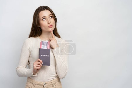 Téléchargez les photos : Pensif belle femme, touriste tenant passeport avec carte d'embarquement prêt pour le voyage, isolé sur fond blanc, espace de copie. Vacances, concept de voyage - en image libre de droit