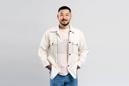 Photo for Portrait of successful Asian businessman wearing modern casual clothes isolated on gray background. Attractive male looking at camera hands in pockets - Royalty Free Image