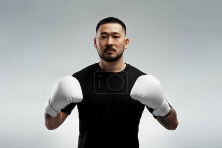Foto de Retrato de un hombre coreano guapo usando guantes de boxeo blancos, parado aislado sobre fondo gris. Atractivo entrenamiento masculino, motivación, estilo de vida - Imagen libre de derechos