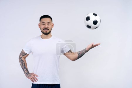 Photo for Portrait of asian motivated sportsman, football player throwing ball looking at camera isolated on white background. Sport, competition, healthy lifestyle concept - Royalty Free Image