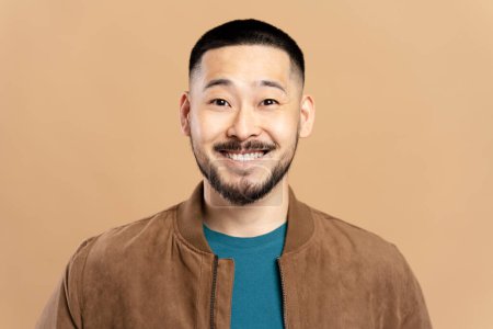 Téléchargez les photos : Portrait d'homme asiatique souriant confiant à la barbe élégante, coiffure veste brune isolée sur fond beige. Joyeux mannequin coréen attrayant regardant caméra, tournage en studio - en image libre de droit